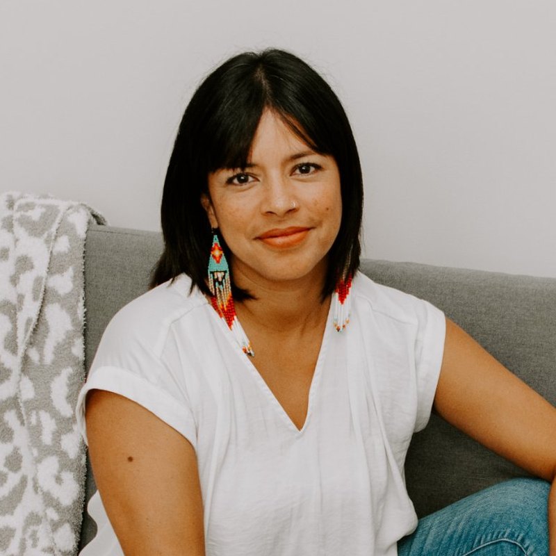 Pema Schott smiling, seated on a gray couch